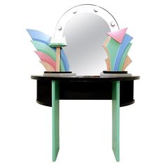 a round mirror sitting on top of a black table next to a green wooden stool