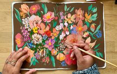 a person is painting flowers on a piece of paper with a brush and watercolor pencil