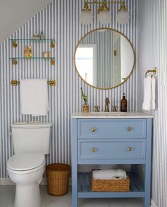 a white toilet sitting next to a blue vanity in a bathroom with striped walls and flooring