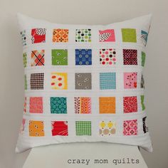 a white pillow with colorful squares on it and the words crazy mom quilts written below