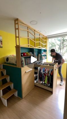 a man standing in front of a closet filled with clothes and other items next to stairs