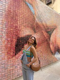 a woman standing in front of a wall with a painting on it's side