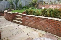 a brick retaining wall with steps leading up to the back yard and landscaping area behind it