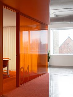 an office with orange walls and red carpeting in front of a large open window