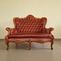 an old fashioned couch sitting on top of a tile floor next to a white wall