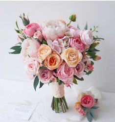 a bouquet of pink and white flowers sitting on top of a table