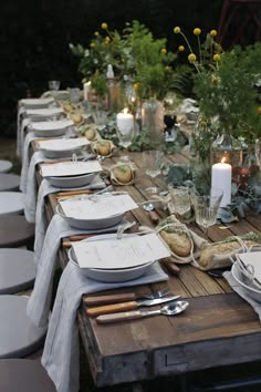 a long table with plates and silverware on it is set up for an outdoor dinner