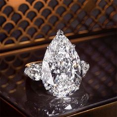 a large diamond ring sitting on top of a black table next to a gold wall