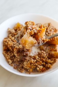 a white bowl filled with oatmeal topped with fruit and crumbs