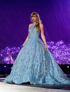 a woman in a blue dress is walking down the runway