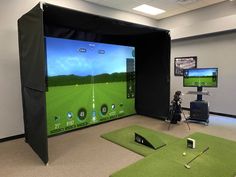 an indoor golf simulator is set up in a room with green carpet and black walls