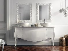 two white sinks sitting on top of a wooden floor next to mirrors and stools