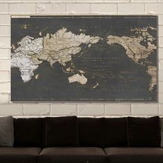 a black and white world map hanging on a brick wall above a brown couch in a living room