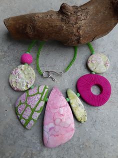 a group of different colored stones sitting on top of a stone floor next to a piece of wood