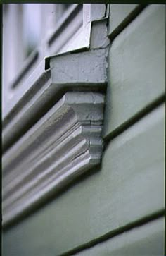 the corner of a house with white trim and green siding on it's side