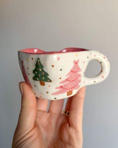 a hand holding a cup with christmas trees on it