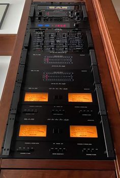 an electronic device sitting on top of a wooden table next to a glass case filled with other electronic devices