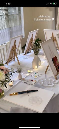 an easel with flowers and pictures on it sitting on a table next to other art supplies