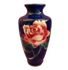 a blue vase with pink flowers painted on the front and sides, against a white background