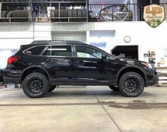 a black suv parked in a garage with large tires on it's rims