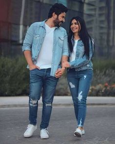 a man and woman are holding hands while walking down the street with their arms around each other