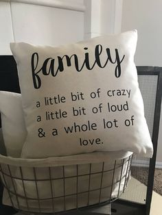 a pillow that says family on it sitting next to a basket with two pillows in it