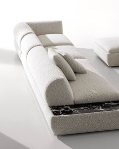 a white couch sitting on top of a floor next to a table with two pillows