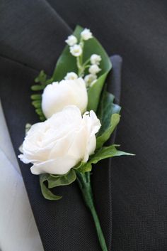 a boutonniere with white flowers and greenery on it's lapel