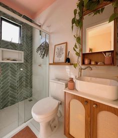 a white toilet sitting next to a walk in shower under a bathroom mirror and sink