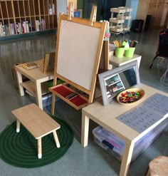 a child's art table with an easel on it and two stools