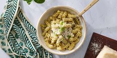 a bowl of pasta with parmesan cheese on top and a wooden spoon next to it