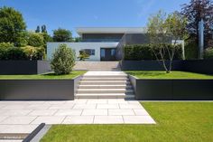 a modern house with landscaping and stairs leading to the front door