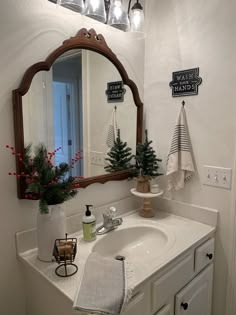 a bathroom sink with a mirror above it and christmas decorations on the counter next to it