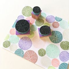 three rubber stamps sitting on top of a piece of paper with circles and leaves printed on it