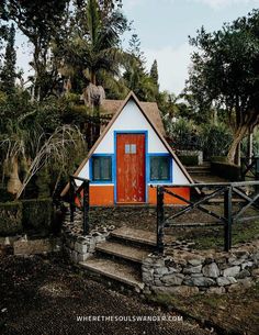 a small white and blue house with red door