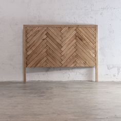 a wooden headboard sitting on top of a hard wood floor next to a white wall