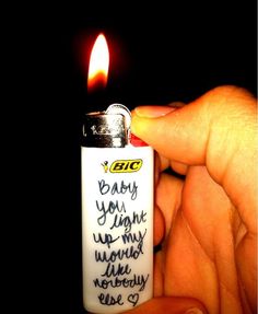 a person holding a lighter with writing on it and a lit candle in the background