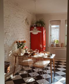 a kitchen with black and white checkered flooring and red refrigerator in the corner