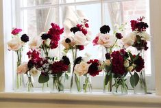 several vases filled with flowers sitting on a window sill