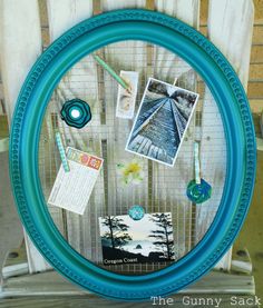 a blue frame with pictures and other items on it in front of a wooden fence