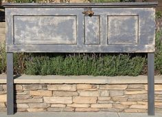 an old wooden cabinet sitting on top of a stone wall next to flowers and plants