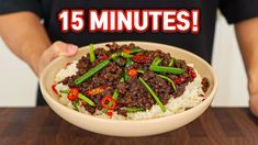 a person holding a bowl filled with beef and rice