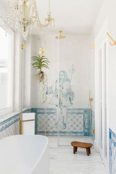 a bathroom with blue and white tiles, a chandelier and a bathtub