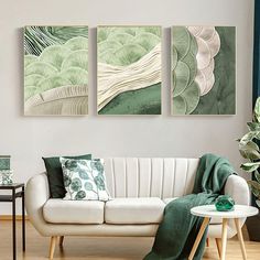 three paintings hang on the wall above a white couch in a room with wood floors