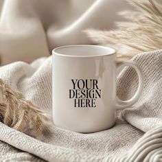 a white coffee mug sitting on top of a blanket