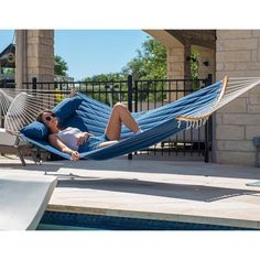 a woman laying in a hammock next to a swimming pool