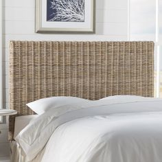 a wicker headboard with white linens in a bedroom next to a window