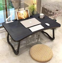 a laptop computer sitting on top of a wooden desk next to a cup of coffee