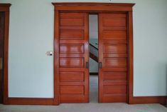 two wooden doors are open in an empty room with carpeted floor and white walls