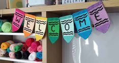 crocheted welcome home banner hanging on the wall in front of bookshelves